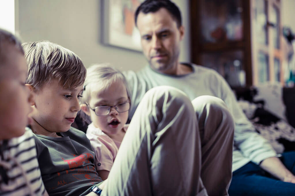 GettyImages-508079955-sml Father with children sitting on couch doing an activity