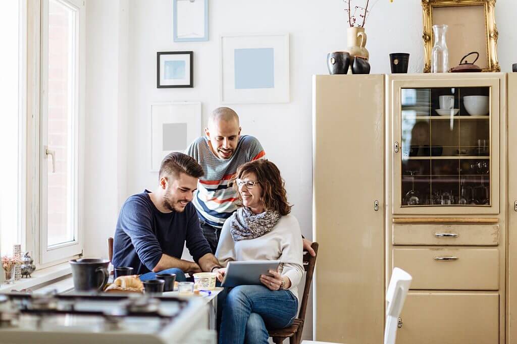 contact Mother with her two sons in the kitchen looking at a book