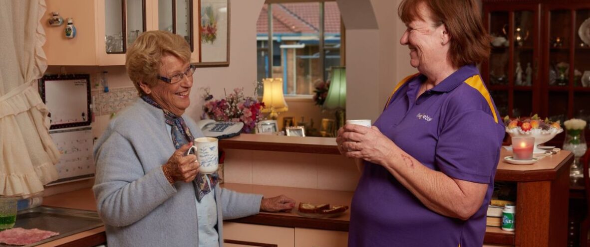 LiveBetter employee having a cup of tea with a customer in the kitchen. Both are smiling