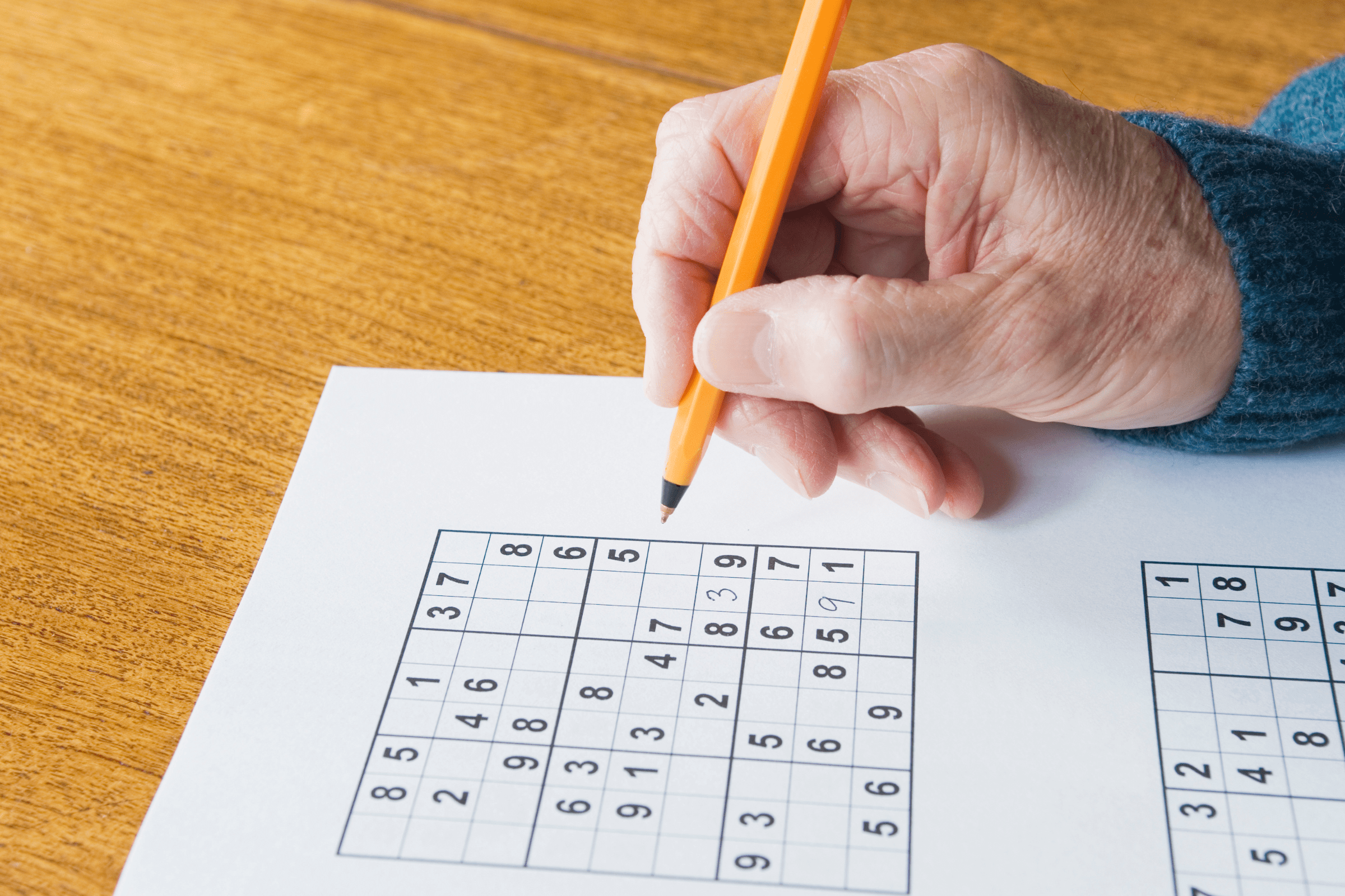 Person filling out a sudoku with a pen