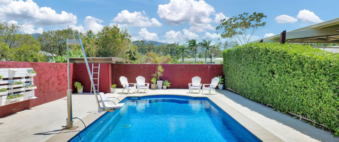 McCabe Coffs Retreat's enclosed pool area, chair lift into pool, bordered by a bold red fence, offering a cosy and secluded atmosphere.