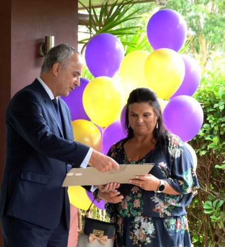 Julie Mccabe being presented with a photo by Peter Mangles at the McCabe Coffs Retreat handing over ceremony. Yellow and purple balloons in the background.